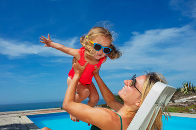 Low angle view of young woman wearing sunglasses against sea against sky