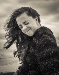 Young woman with eyes closed at beach during windy weather
