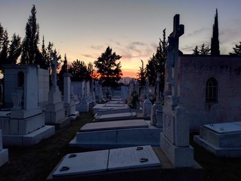 View of cemetery and buildings against sky at sunset