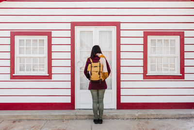 Back view of backpacker woman in front of colorful houses.promenade of costa nova, aveiro, portugal