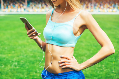 Midsection of woman using mobile phone in grass