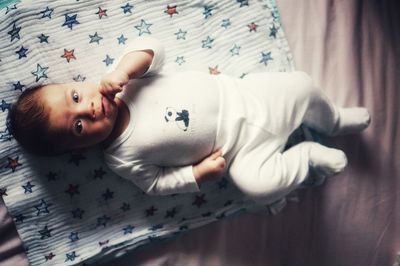 High angle view portrait of baby boy lying on bed at home