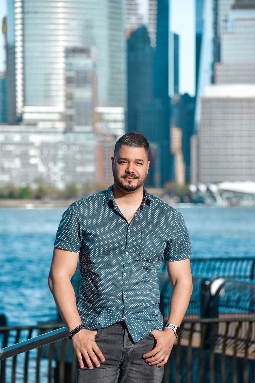 architecture, building exterior, one person, built structure, standing, portrait, city, focus on foreground, looking at camera, real people, front view, railing, young adult, connection, young men, wireless technology, building, day, office building exterior, outdoors, skyscraper