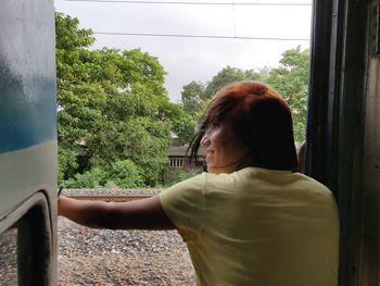 Rear view of woman looking through window