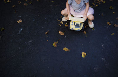 Low section of playful girl driving toy car on road