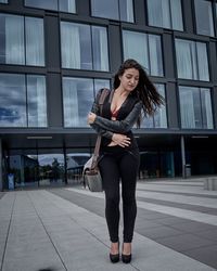 Full length of fashionable woman standing against building in city