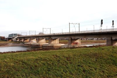 Bridge over river amidst field against sky