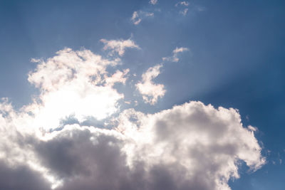 Low angle view of sunlight streaming through clouds