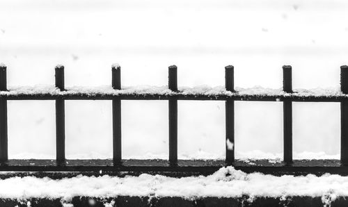 Close-up of snow covered railing against sky