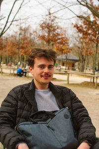 Portrait of young man sitting in a chair in a park