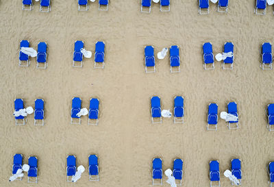 Aerial top view of a beach with white umbrellas and blue lounge chairs