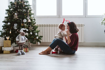 Baby girl with mother sitting at home during christmas