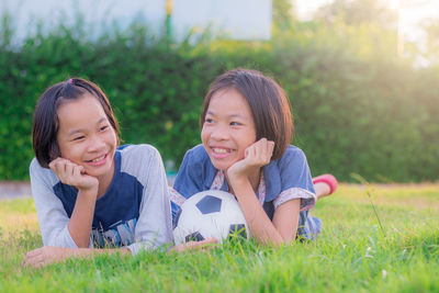 Smiling girls with soccer ball lying on grass