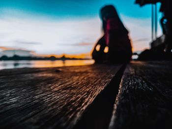 Woman sitting on pier over sea against sky