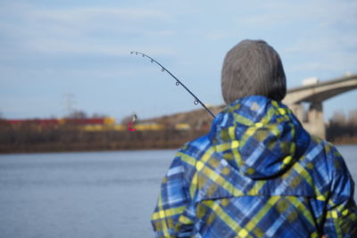 Rear view of man standing by lake