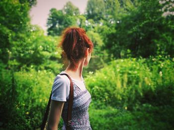 Side view of mid adult woman standing against trees in forest