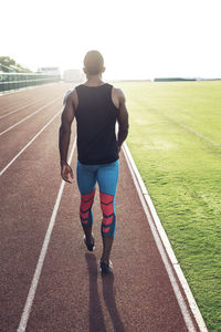 Rear view of sportsman walking on running tracks