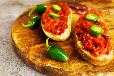 Slices of fresh bread spread with homemade lutenica on a wooden board