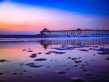 Pier over sea against sky during sunset