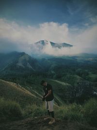 Rear view of man standing on mountain against sky