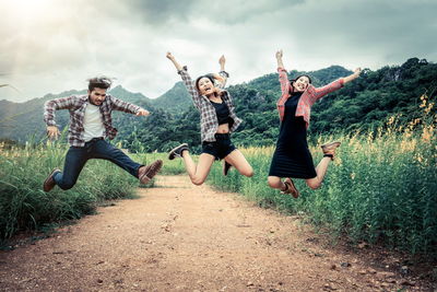 Friends jumping against plants