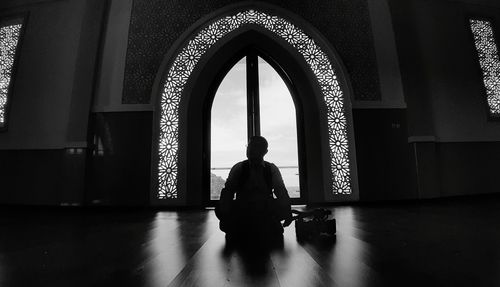 Rear view of man sitting in corridor of building