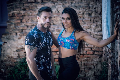 Portrait of young couple standing against wall