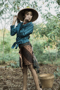 Full length of woman wearing hat standing against plants