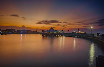 Illuminated bridge over bay against sky during sunset