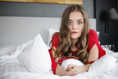 Portrait of young woman relaxing on bed at home