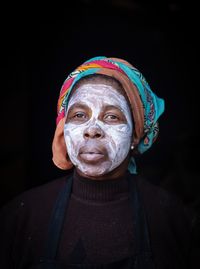 Portrait of man wearing mask against black background