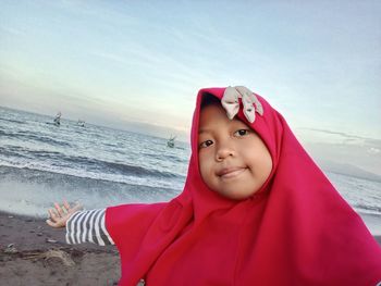 Portrait of young woman standing against sea