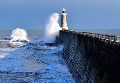 Waves splashing on shore against clear blue sky