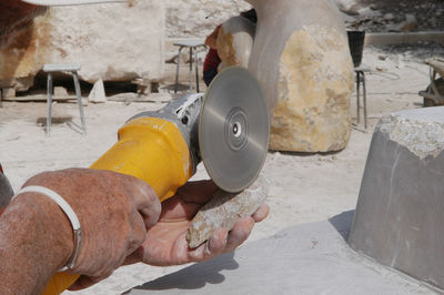 Cropped hand of man cutting rock
