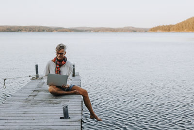 Woman on jetty using laptop