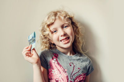 Caucasian blonde girl showing her missing tooth in a mouth and holding money from tooth fairy. 