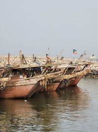 Fishing boats moored in sea against clear sky