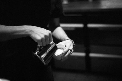 Midsection of barista making pattern on coffee