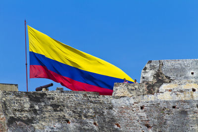 Low angle view of yellow flag against blue sky