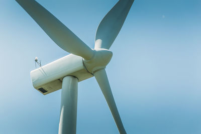 Low angle view of wind turbine against clear blue sky