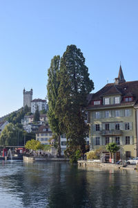 Buildings by river in city against clear sky