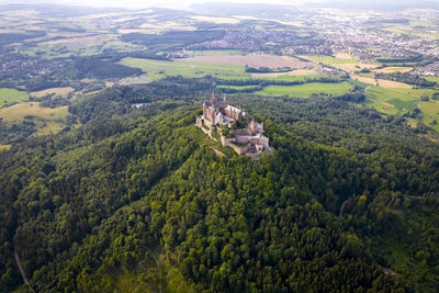 Drone shot of hohenzollern castle on forested mountain top in the swabian alps in summer