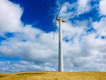 Low angle view of windmill on field against sky