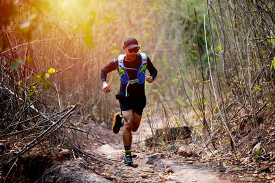 Full length of man running on footpath in forest