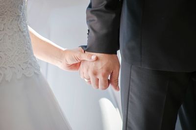 Midsection of couple holding hands during wedding ceremony