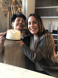 Portrait of smiling mother and daughter with cake