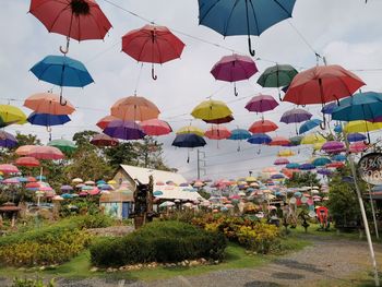 Multi colored umbrellas hanging against sky