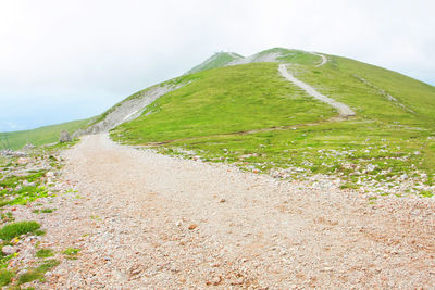 Scenic view of hill against cloudy sky