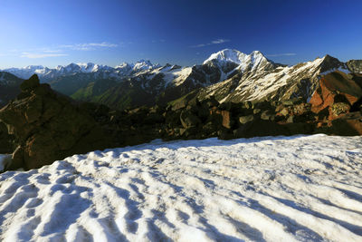 Scenic view of snow covered mountains against blue sky