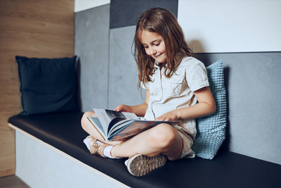 Schoolgirl reading book in school library. primary school pupil is involved in book. doing homework